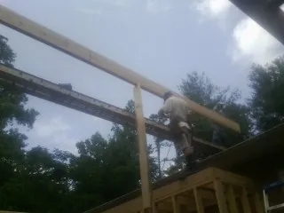 Carpenter setting a ridge beam over a new addition frame — Ice Dam Removal by Roofing Brothers in Montross
