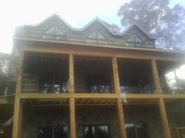 Dormers and porch framing on a large log home under construction — Roof Coating work by our crew in Montross