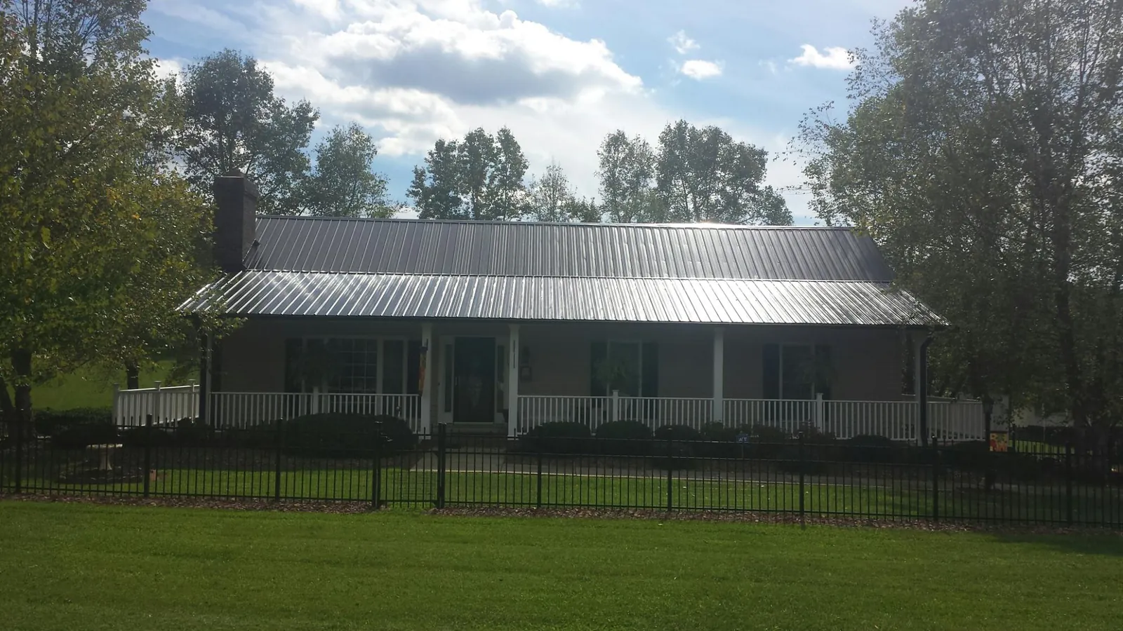 Gray metal roof on a brick ranch with a full width front porch — Gutter Guard Installation work by our crew in Montross