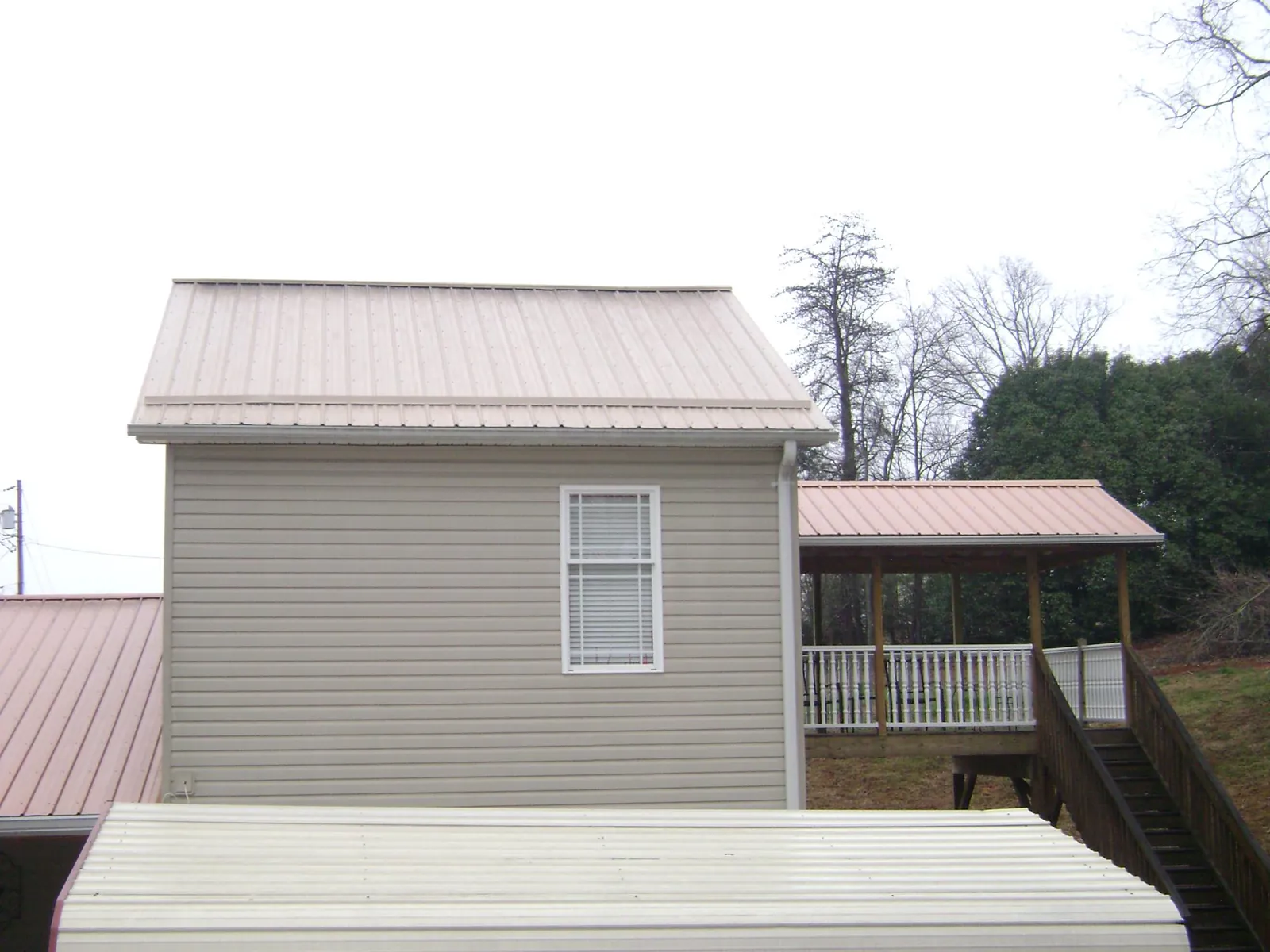 Tan metal roofs on a two story addition and attached porch, from a Roof Replacement job in Montross