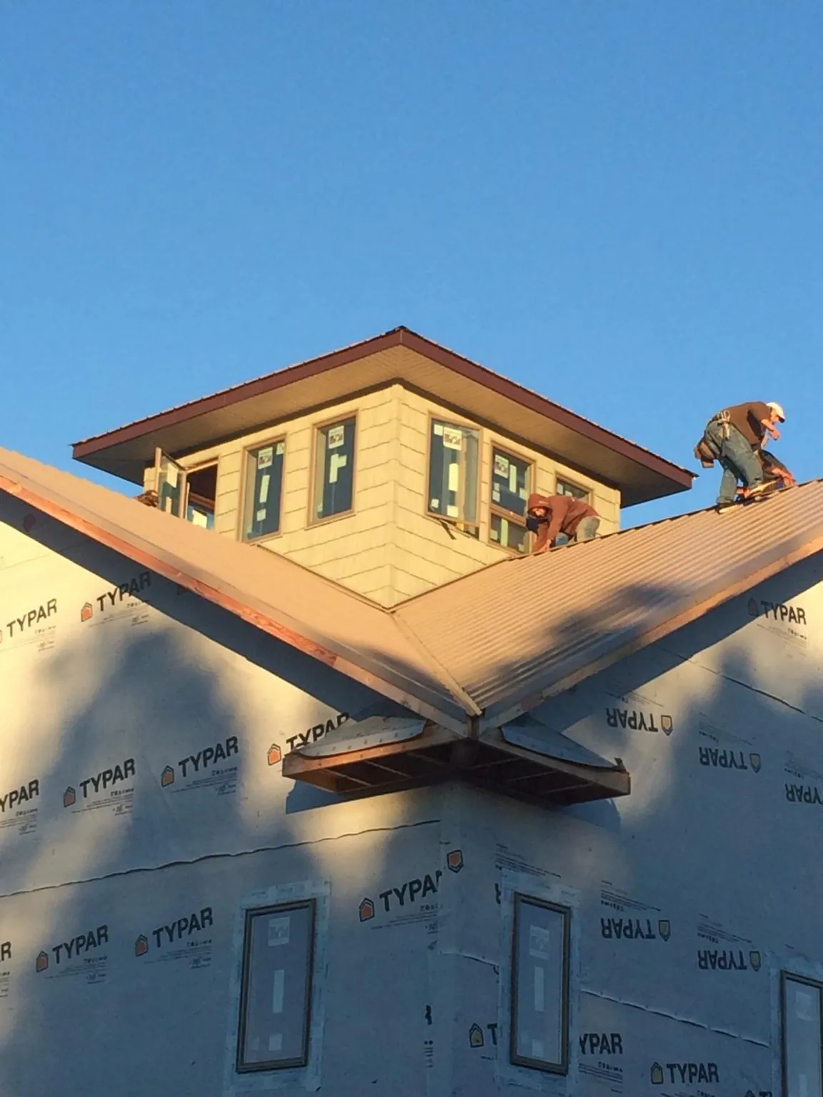 Roofers working around a rooftop cupola on a new metal roof at sunset — Roof Waterproofing in Montross by Roofing Brothers